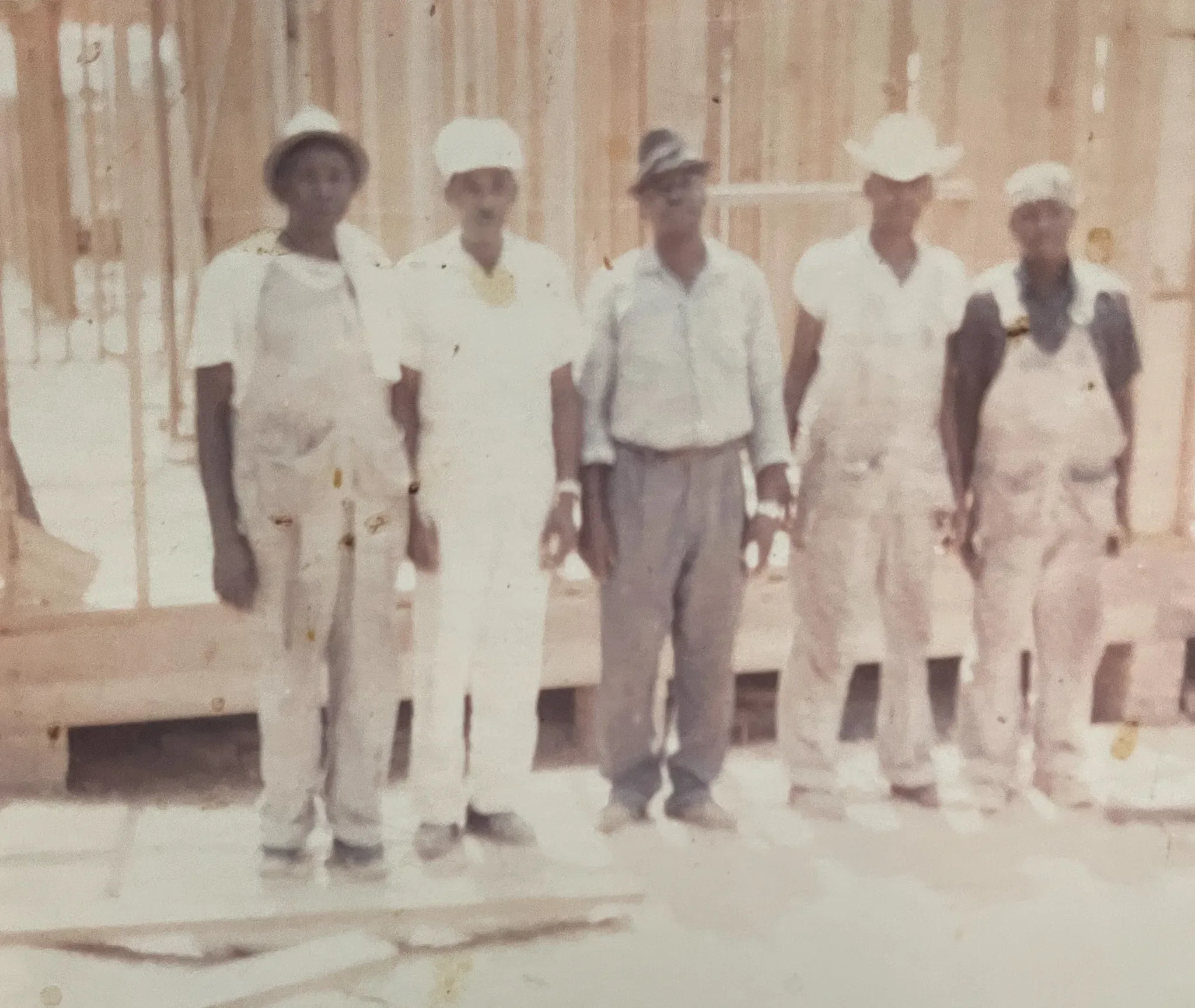 Five individuals in work attire, including hard hats, posing at a construction site.